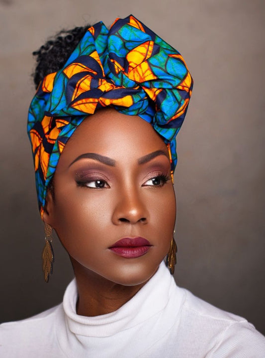 Zalika wire headwrap in colorful African print, wrapped around natural curly hair, worn by a woman in a white turtleneck.